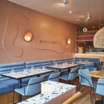 Blue leather banquettes beneath the Bocca Bocca wall sign 