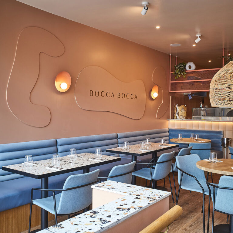 Blue leather banquettes beneath the Bocca Bocca wall sign 