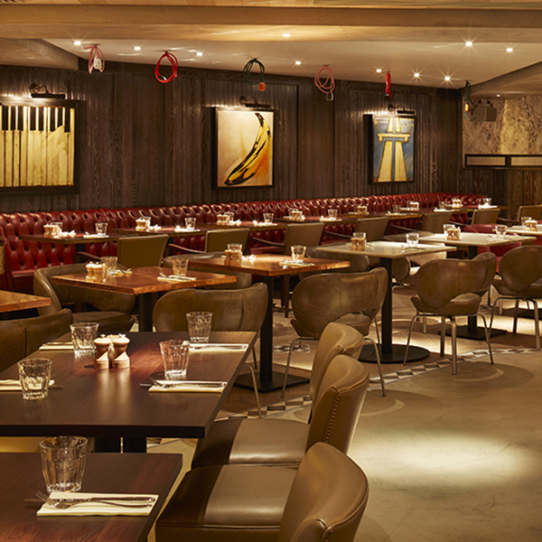 Restaurant floor with leather banquettes and tan leather chairs at 100 Wardour Street