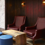 Two burgundy leather armchairs in a panelled corner at 100 Wardour Street