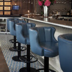 Row of blue leather bar stools at the counter of 28°-50° Wine Workshop & Kitchen
